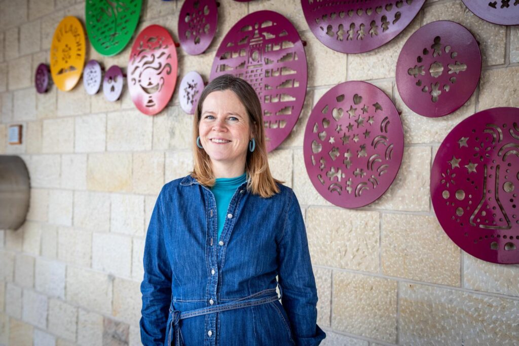 Louise Kirby smiling with a background of decorative metal circles on a wall